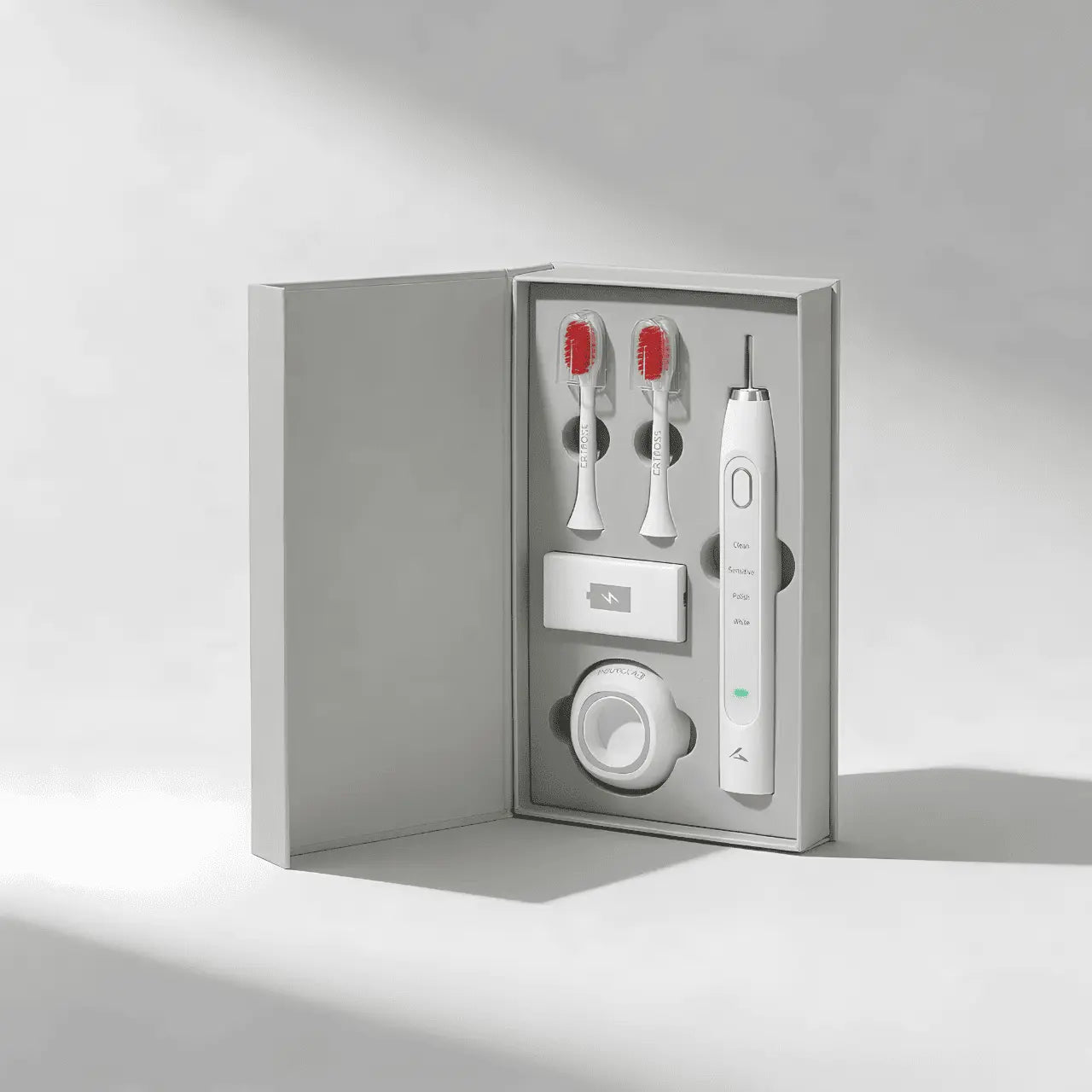 Red light toothbrush set with two brush heads and a charger in a gray box on a light gray background