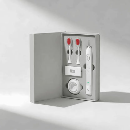 Red light toothbrush set with two brush heads and a charger in a gray box on a light gray background